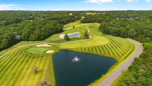 An aerial view of a golf course with a pond, sand bunkers, and a winding path. - White Oak Hollow - newly updated (Innsbrook)