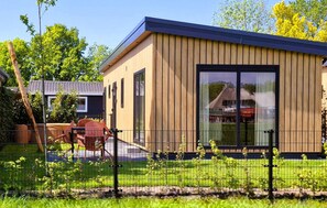 Un bâtiment moderne doté de grandes fenêtres, d’une façade en bois et d’une clôture en métal à l’avant.