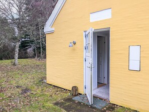 A yellow building with a white door, a small window, and a doorbell.