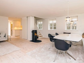 Ein modernes Wohnzimmer mit Kamin, einer Essecke mit rundem Tisch und einer Treppe zu einer weiteren Ebene.