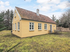 Ein gelbes Haus mit einem Ziegeldach, weißen Fenstern und einem Schornstein.