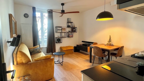 Ein modernes Wohnzimmer mit einer Couch, einem Esstisch und einer Küchenzeile.