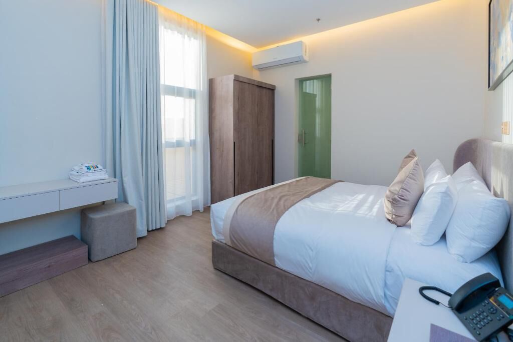 Une chambre d’hôtel moderne équipée d’un lit, d’une table de chevet et d’un téléphone.