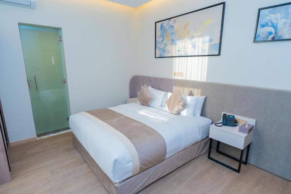 Une chambre d’hôtel avec un lit, une table de chevet et une œuvre d’art au mur.