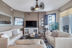 Ein Wohnzimmer mit zwei Sofas, einem Couchtisch, einem Fernseher und einem Deckenventilator.