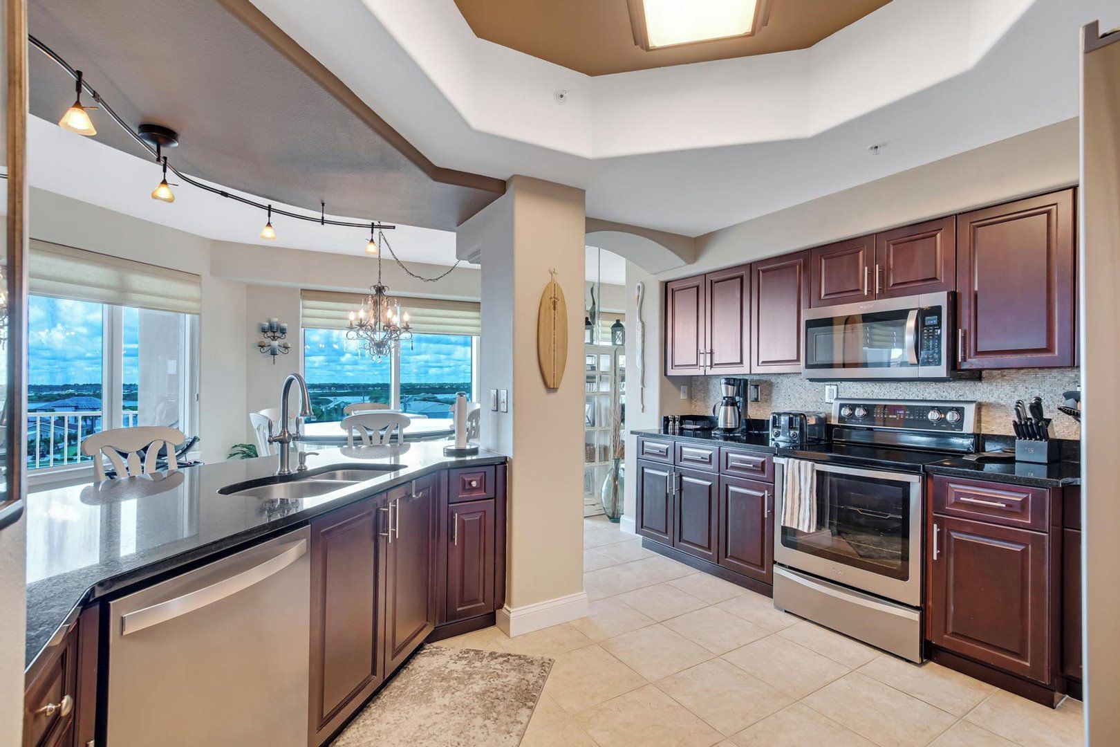 A modern kitchen with dark wood cabinets, stainless steel appliances, and a large island with a sink.