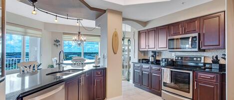 A modern kitchen with dark wood cabinets, stainless steel appliances, and a large island with a sink.