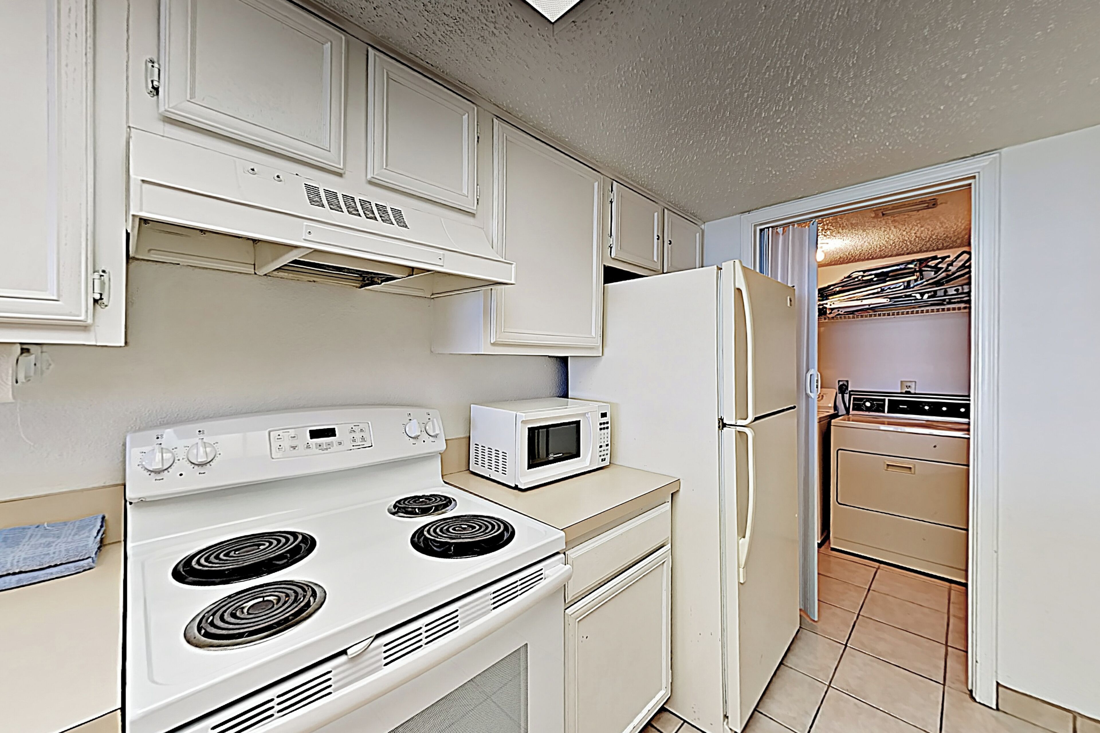 A kitchen with white appliances, including a stove, microwave, and refrigerator.