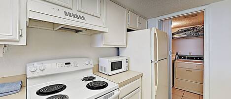 A kitchen with white appliances, including a stove, microwave, and refrigerator.