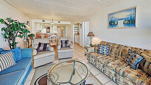 A living room with a sofa, armchair, and coffee table. There is a dining area in the background with a table and chairs. - Gulf-view Resort Retreat: Suntide III - Unit 209 (South Padre Island)