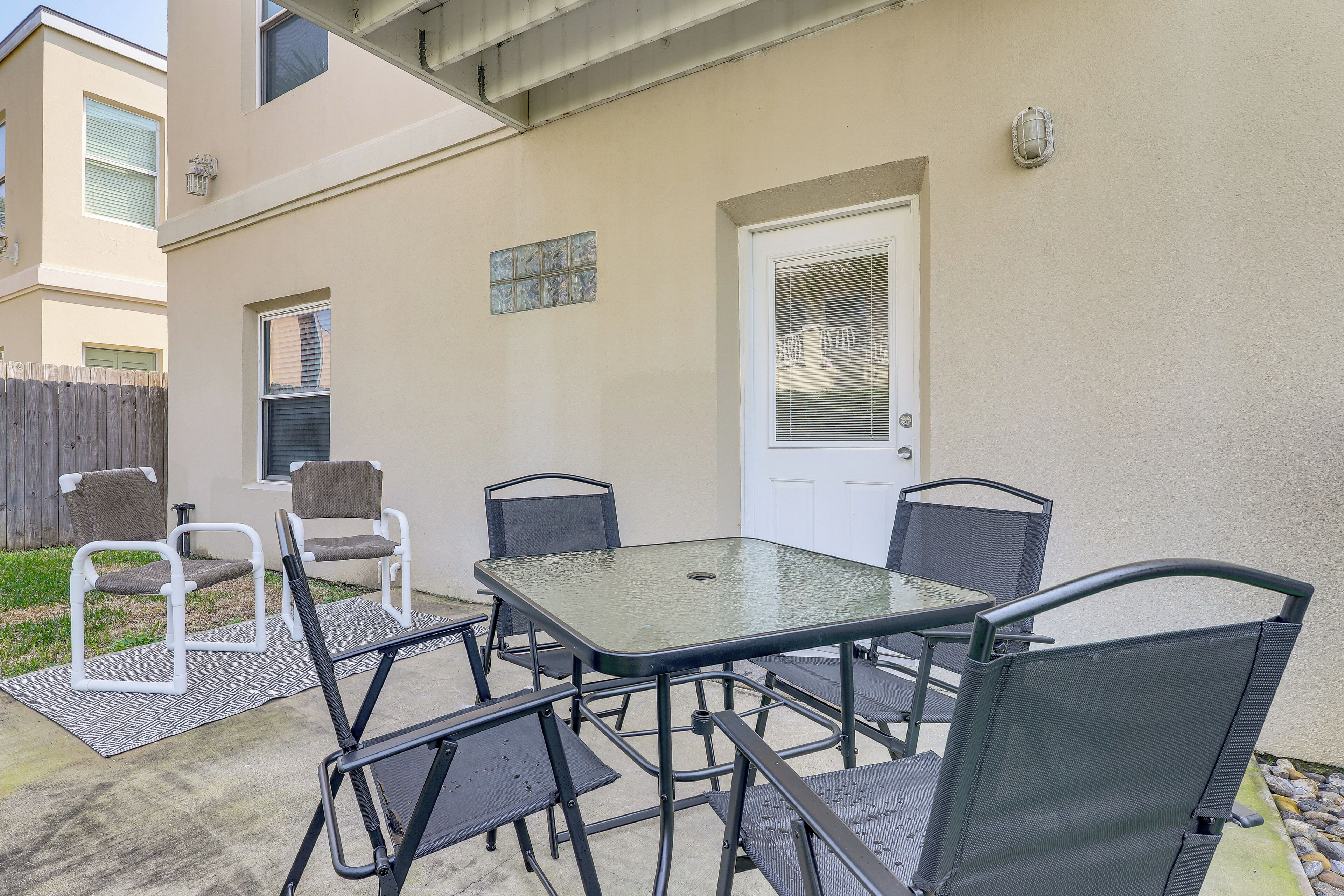 An outdoor patio with a table and chairs, a door, and a small window.