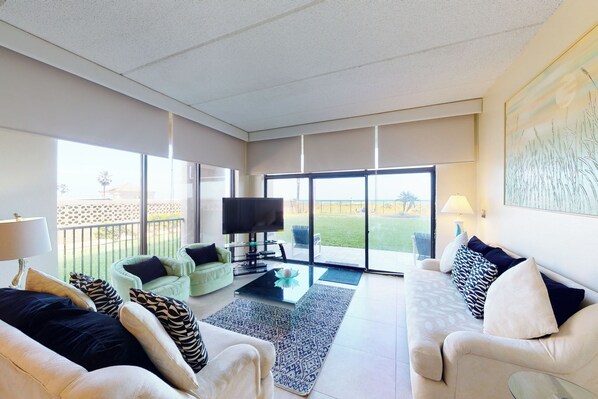 Een ruime woonkamer met een bank, fauteuils, een salontafel en een televisie.