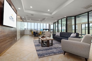 A spacious lobby with a dining area, a sofa, and a large window offering a view. - Gulf-view 3br, Patio, Yard: Suntide III - Unit 101 (South Padre Island)