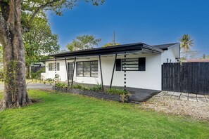 A single-story house with a white exterior, black shutters, and a black roof.