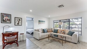 A modern living room with a sectional sofa, a wooden bench, a glass coffee table, and artwork on the walls.