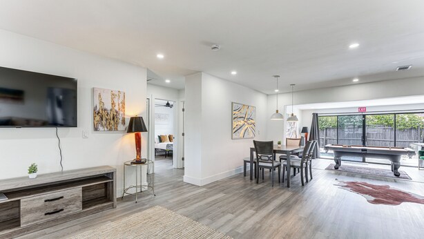 A modern living room with a flat-screen TV, a pool table, and a dining area.