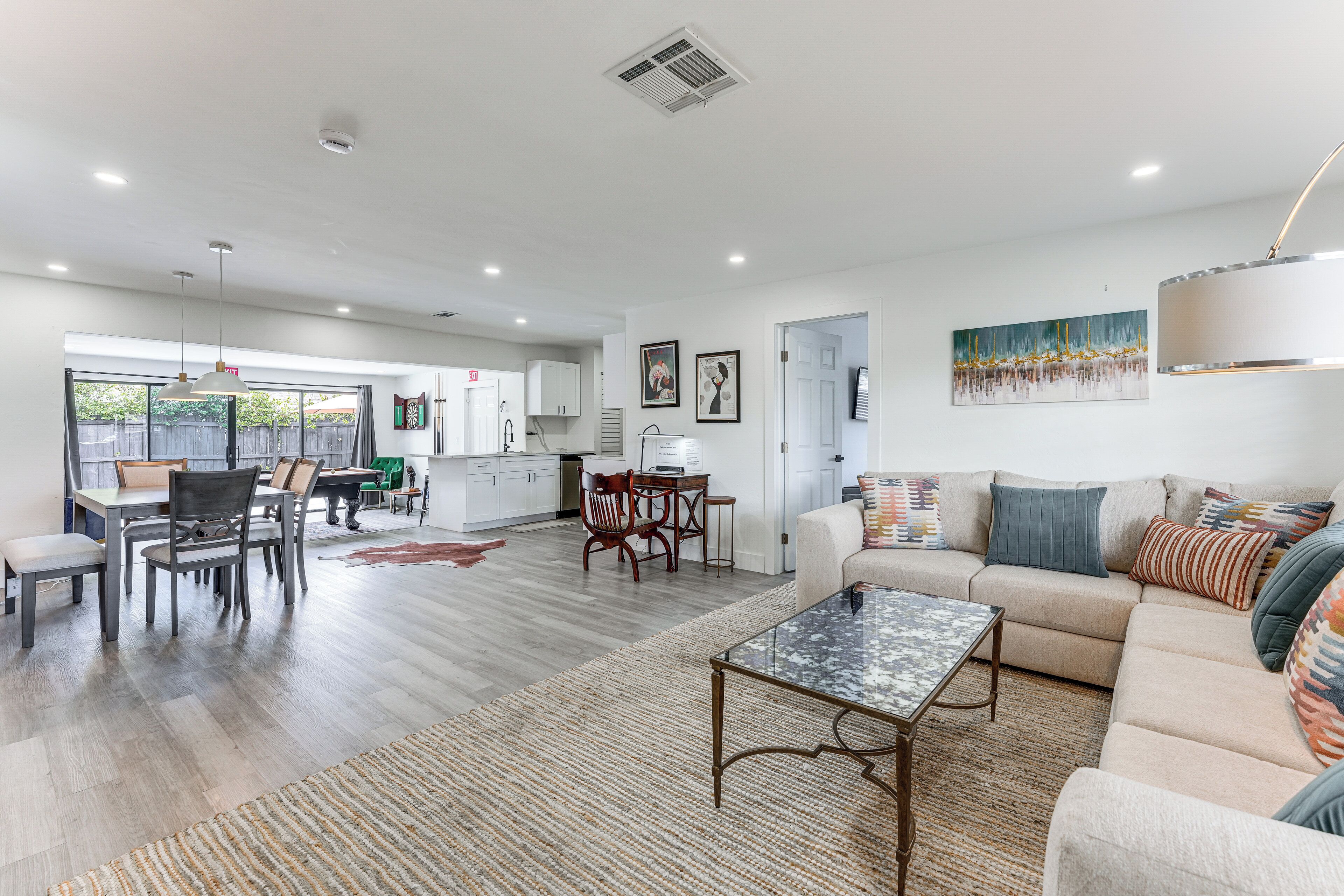 A spacious living area with a sofa, coffee table, and dining area with chairs and a table.