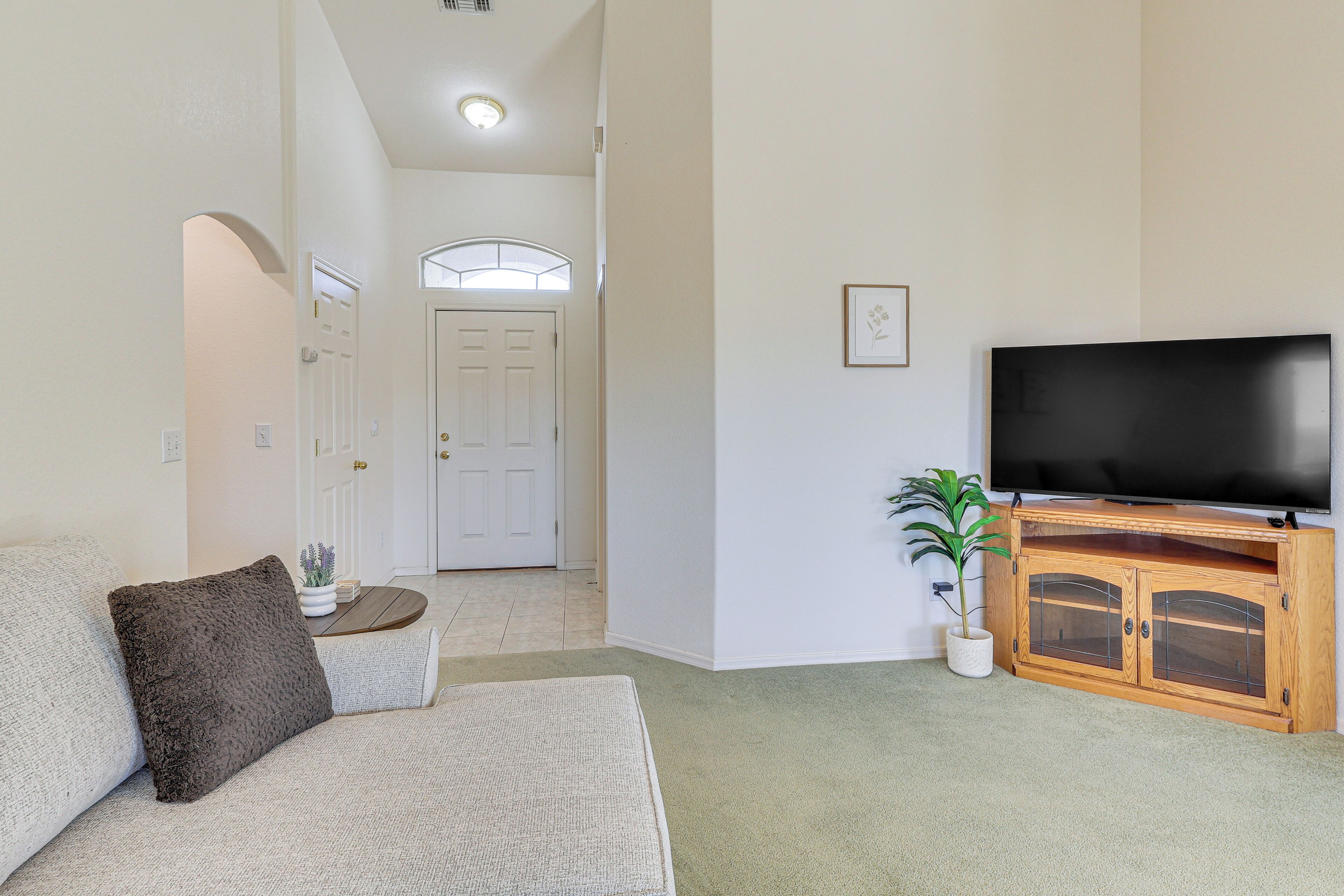 A living room with a sofa, a television on a wooden cabinet, and a potted plant.