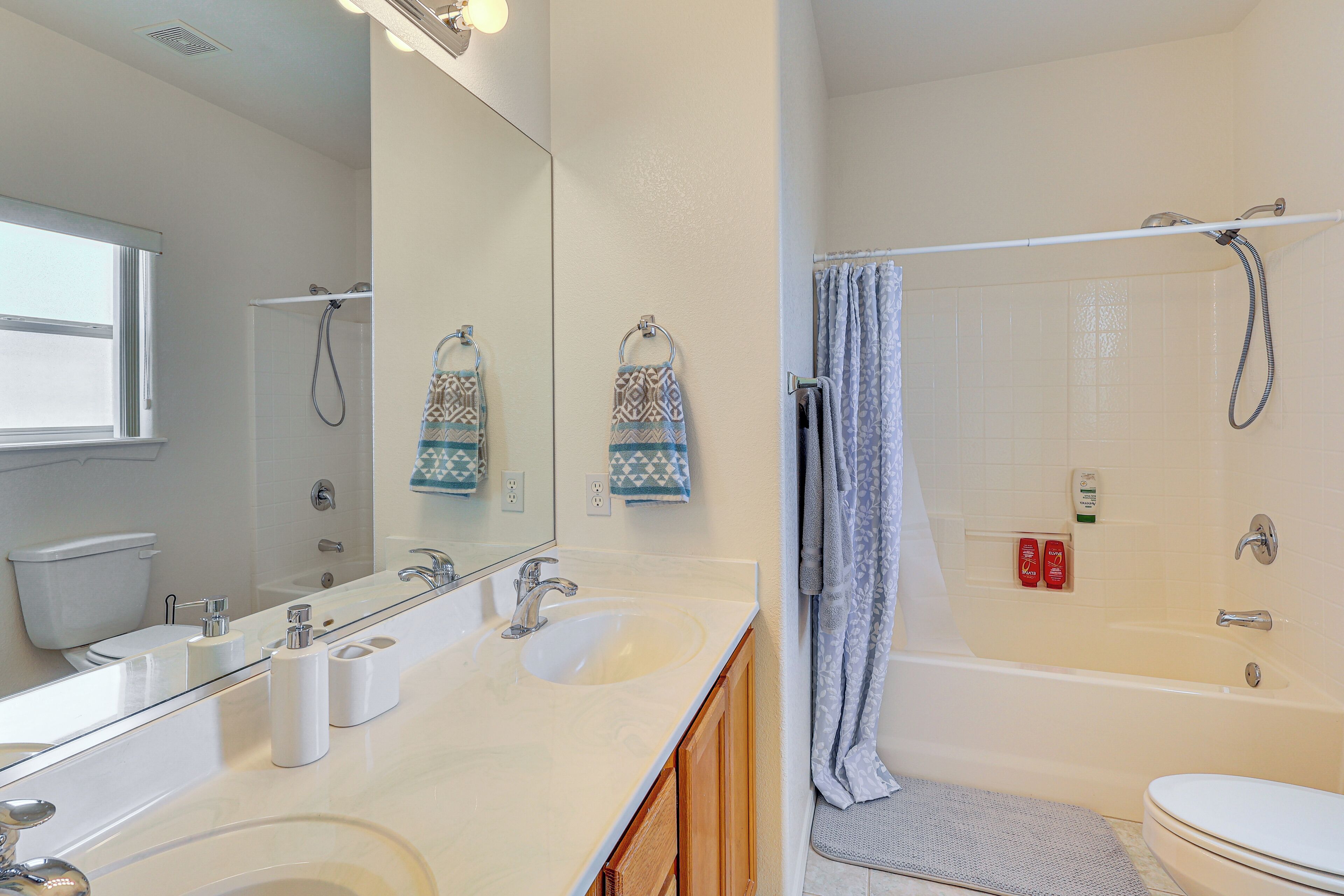 A bathroom with two sinks, a large mirror, a bathtub, and a shower.