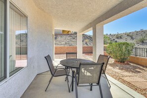Eine Außenpatio mit einem runden Tisch, vier Stühlen, einer Glastür und Blick auf eine hügelige Landschaft.