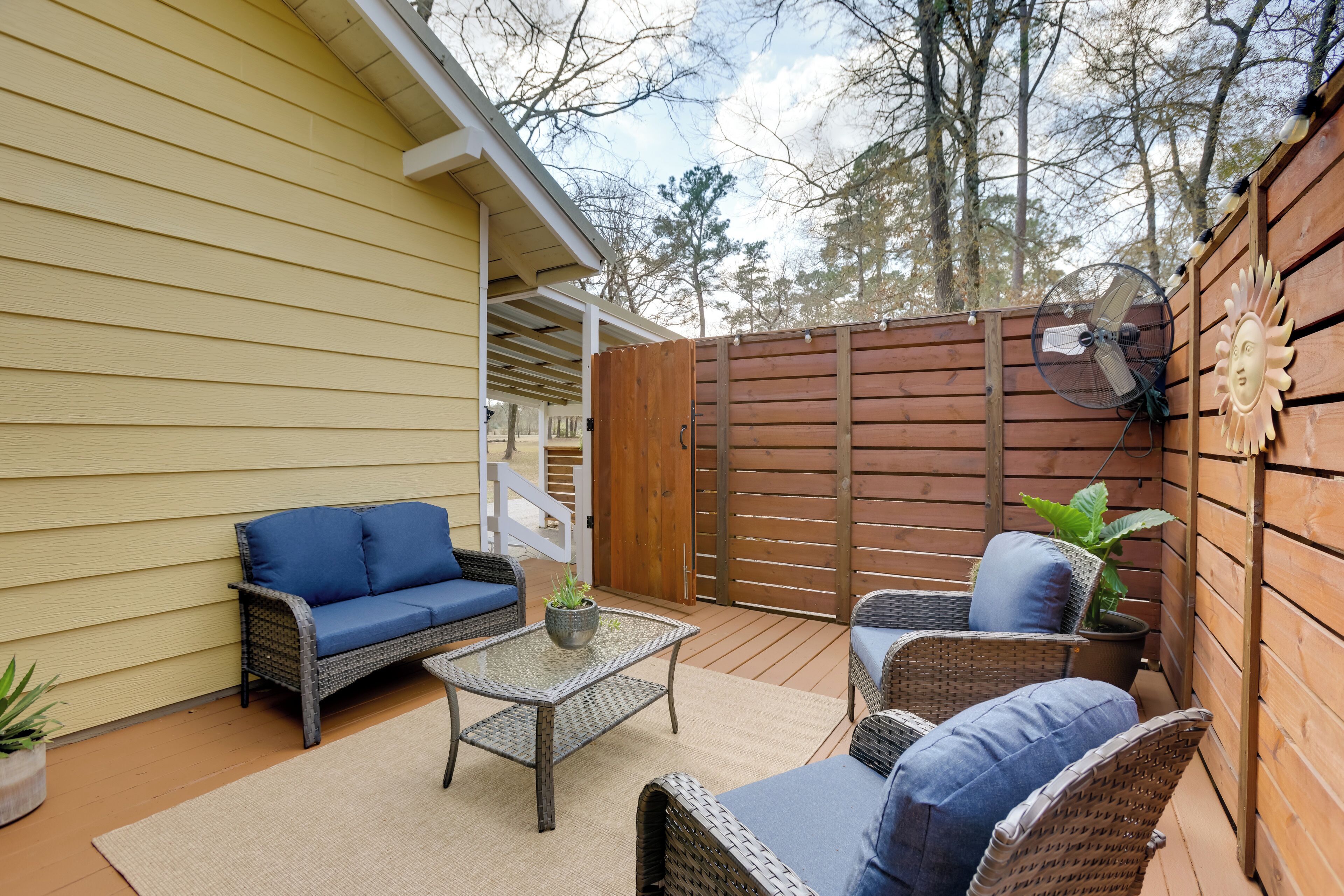 A patio with wicker furniture, a fan, and a potted plant.
