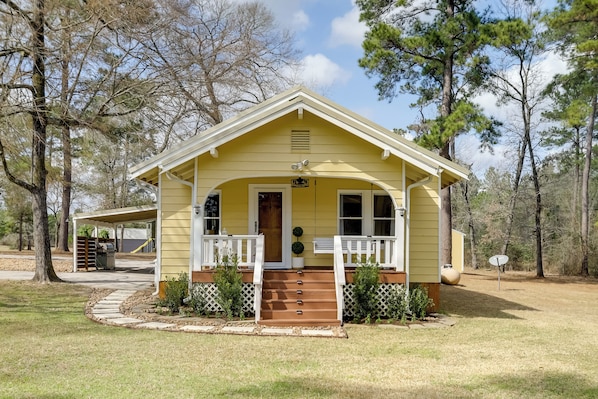 A yellow single-story house with a porch, a front door, and a small front yard.