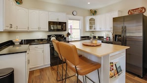 A kitchen with white cabinets, a stainless steel refrigerator, a wooden island, and a clock on the wall. - Walk to Fishing Pond! Wooded Montgomery Retreat (Montgomery)