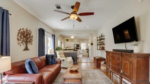 A living room with a leather sofa, wooden coffee table, and a television on a wooden cabinet. - Walk to Fishing Pond! Wooded Montgomery Retreat (Montgomery)