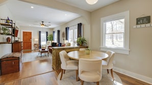A spacious living room with a round dining table, a kitchen area, and a large window. - Walk to Fishing Pond! Wooded Montgomery Retreat (Montgomery)
