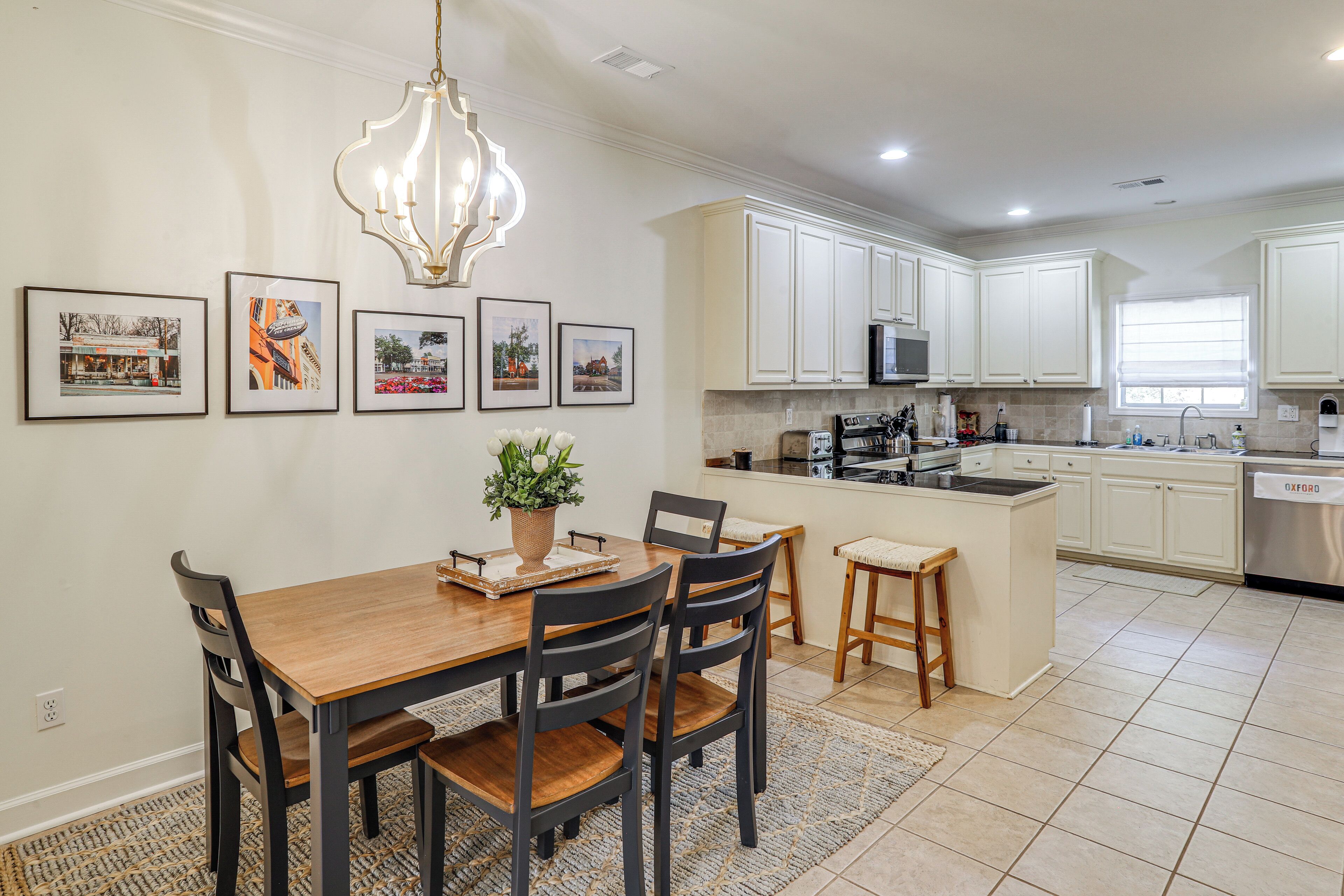 A modern kitchen with white cabinets, a central island, and a dining area with a wooden table and chairs.