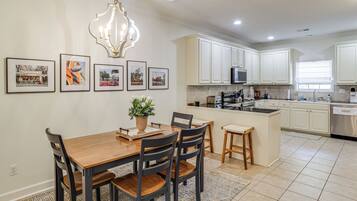 A modern kitchen with white cabinets, a central island, and a dining area with a wooden table and chairs.
