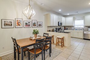 A modern kitchen with white cabinets, a central island, and a dining area with a wooden table and chairs. - Oxford Blues: Spin Records Between Rebel Kickoffs (Oxford)