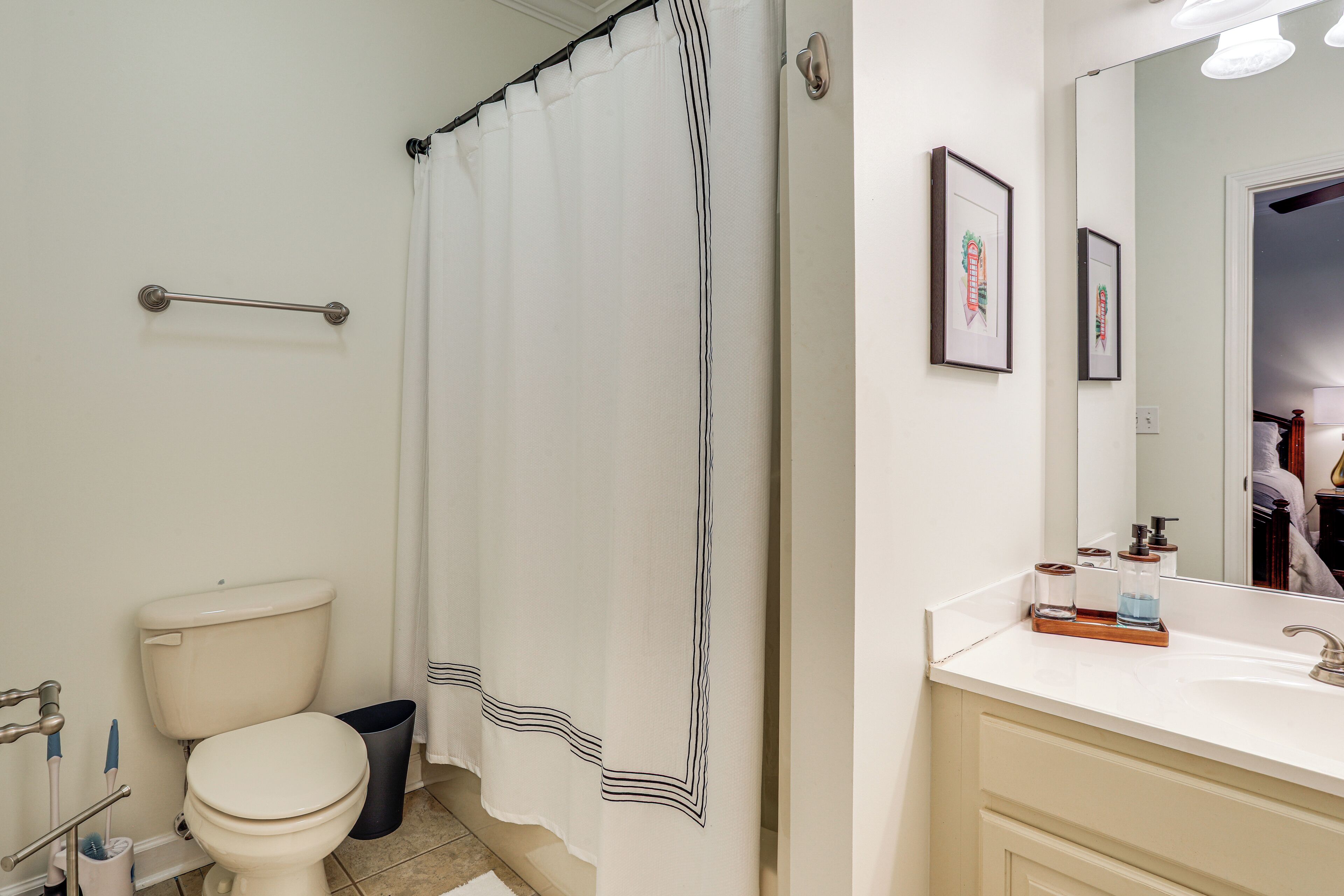 A bathroom with a toilet, a shower curtain, a sink, and a mirror.