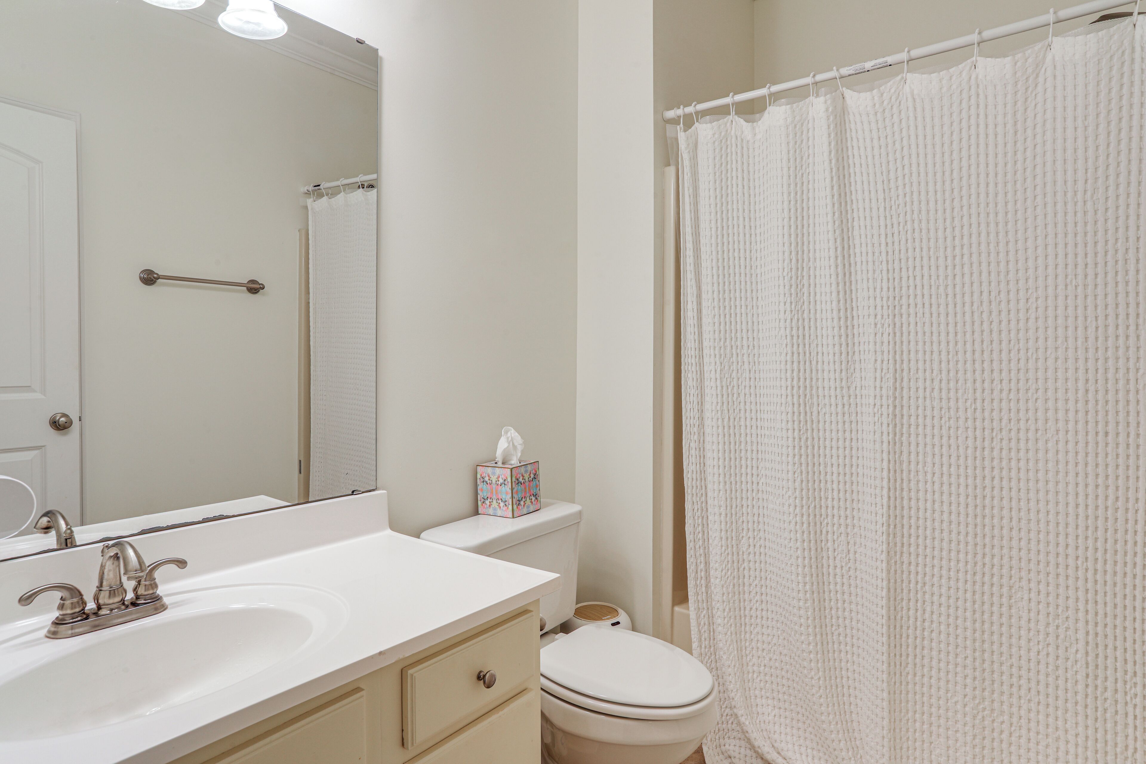 A bathroom with a white sink, mirror, and toilet.