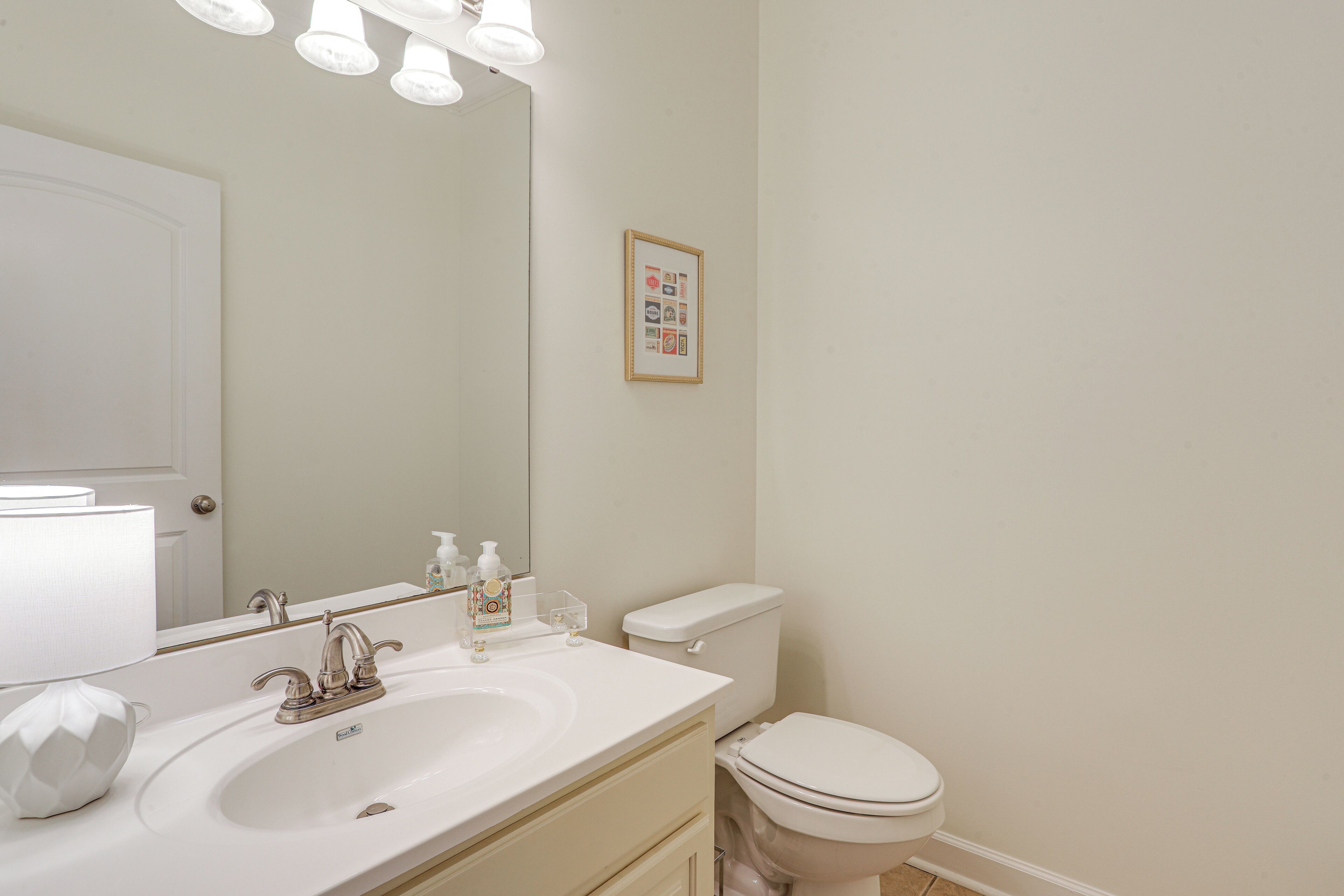 A bathroom with a white sink, mirror, and toilet.