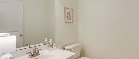 A bathroom with a white sink, mirror, and toilet.