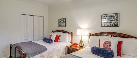 A bedroom with two beds, a ceiling fan, a nightstand, and a wall with a framed picture.