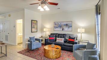 A living room with a ceiling fan, two sofas, a coffee table, and a patterned rug.