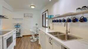 A modern kitchen with white cabinetry, stainless steel appliances, and a wall-mounted pot rack. - Family Fun on Cross Lake! Fire Pit, Games, Grill (Pine City)