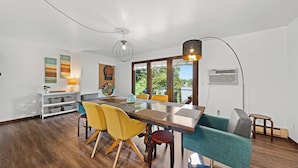 A modern dining area with a wooden table, yellow and teal chairs, and a pendant light. - Family Fun on Cross Lake! Fire Pit, Games, Grill (Pine City)