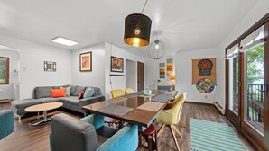 A modern living room with a dining area, large windows, and a view of the outdoors. - Family Fun on Cross Lake! Fire Pit, Games, Grill (Pine City)