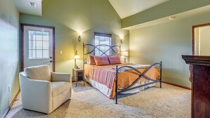 A bedroom with a bed, a chair, a nightstand, and a dresser.