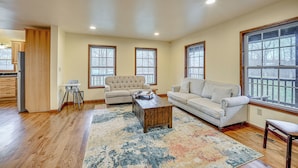A spacious living room with a wooden floor, two sofas, a coffee table, and large windows.