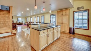 A spacious kitchen with wooden cabinets, a large island, and pendant lighting.