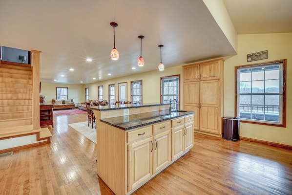 A spacious kitchen with wooden cabinets, a large island, and pendant lighting. - Private Hot Tub & Games Galore! Hamden Family Home (McArthur)