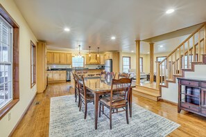 A spacious kitchen with wooden cabinets, a dining area with a glass table, and a staircase leading to another level. - Private Hot Tub & Games Galore! Hamden Family Home (McArthur)