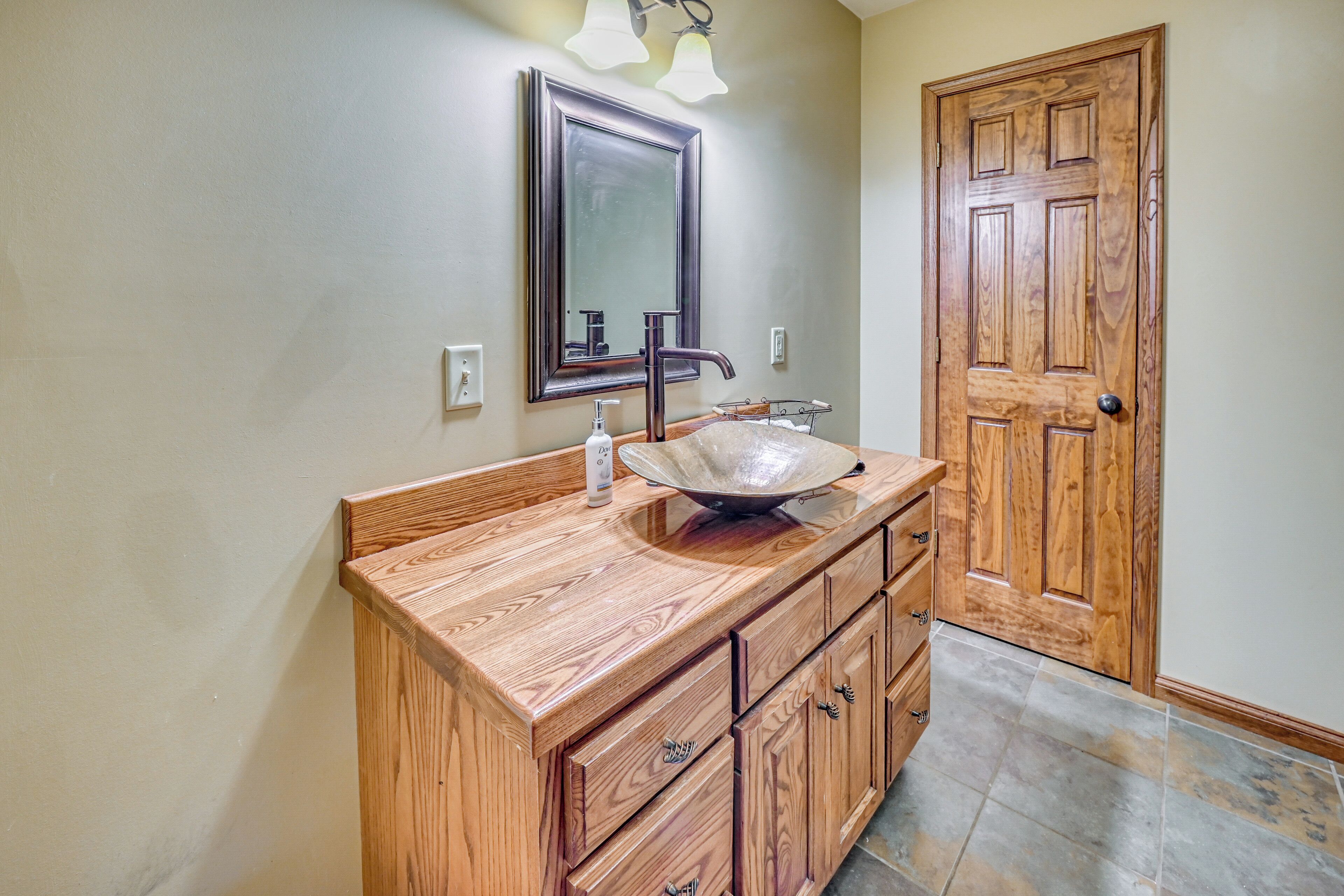 A bathroom with a wooden vanity, a large mirror, and a sink.