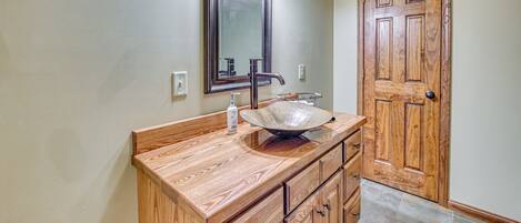 A bathroom with a wooden vanity, a large mirror, and a sink.