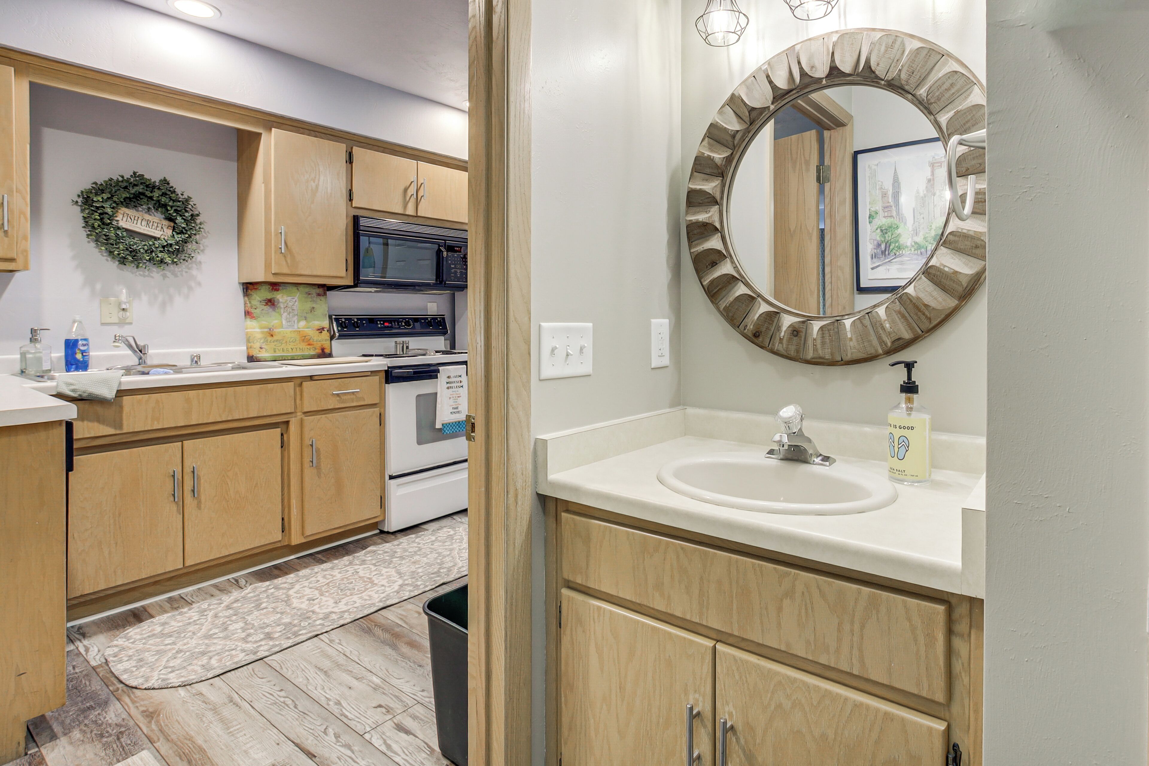 A kitchen with wooden cabinets, a microwave, oven, and a sink with a mirror above it.