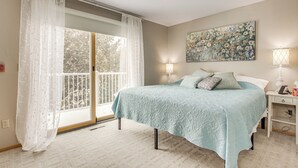 Une chambre à coucher avec un lit, une fenêtre avec des rideaux, un tableau au mur et une table de chevet avec une lampe.
